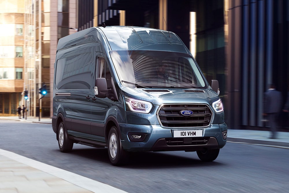 Fourgon Ford Transit bleu circulant dans une ville.