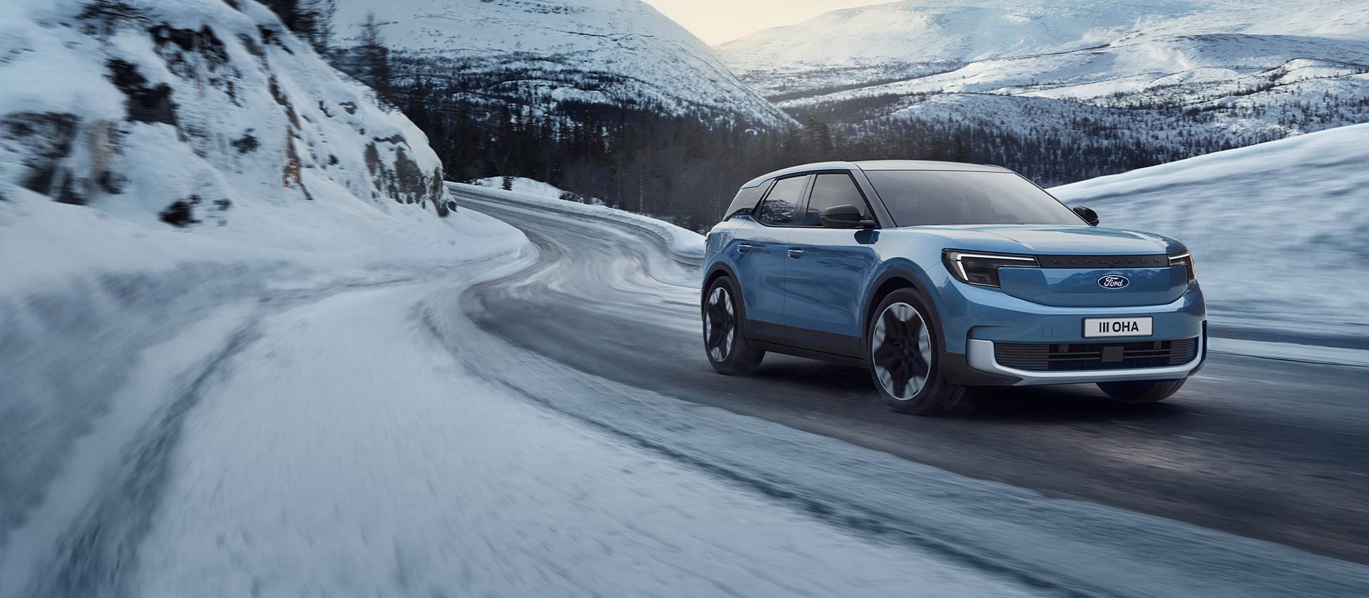Le Ford Explorer électrique bleu sur une route de montagne enneigée, mettant en évidence sa capacité et son autonomie dans des conditions hivernales.