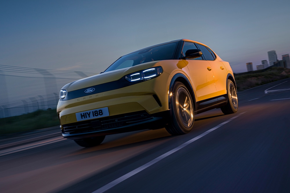 Une Ford Capri électrique jaune roulant sur une route ouverte.