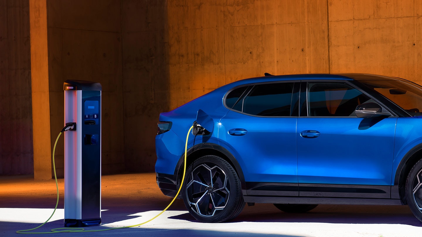 Un véhicule électrique Ford Capri bleu branché sur un chargeur.