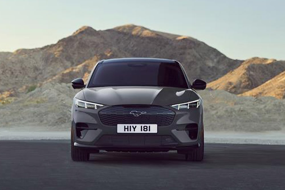 Vue avant d’une Ford Mustang Mach-E noire, garée devant un paysage montagneux.