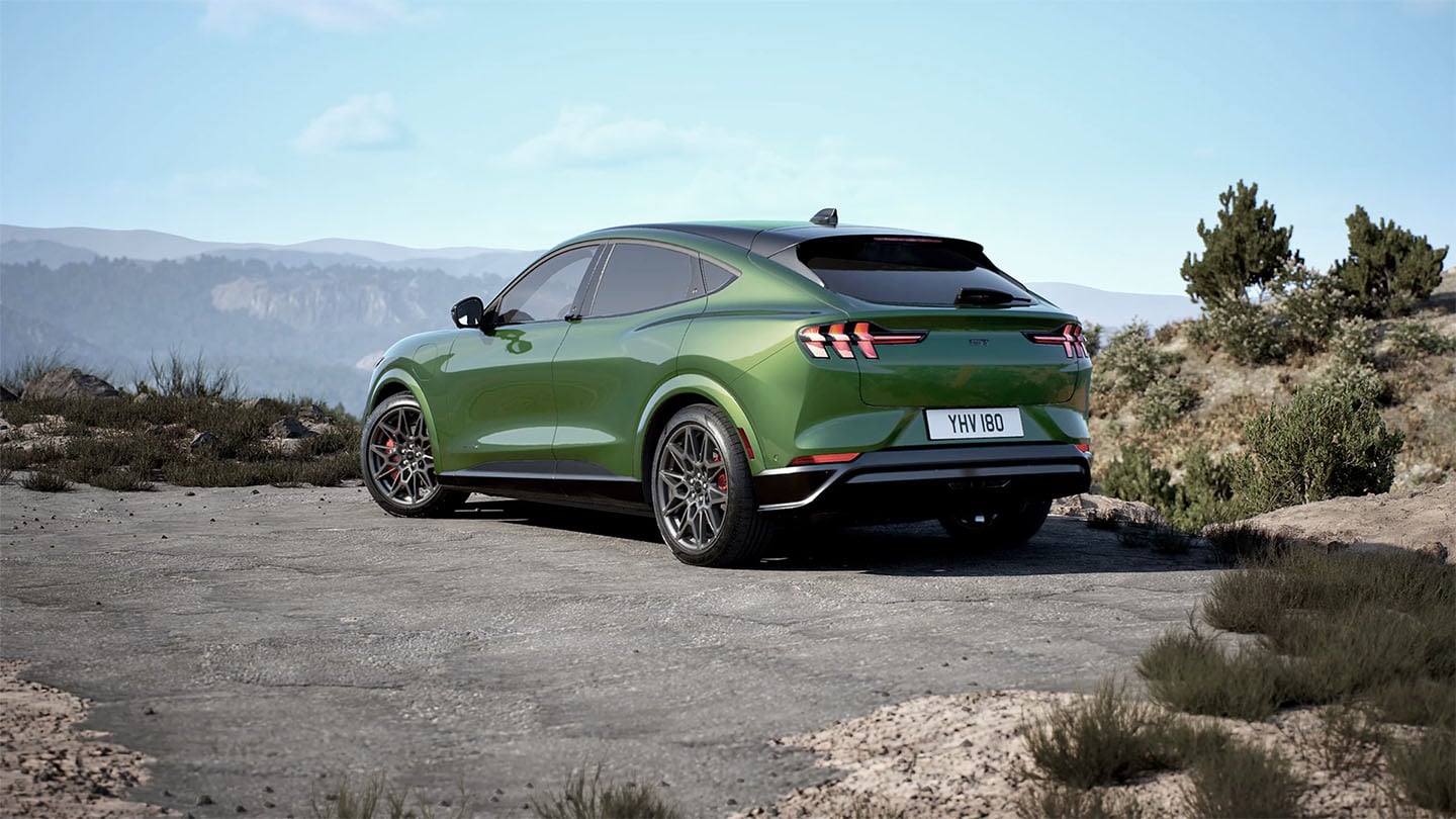 De achterkant van de Ford Mustang Mach-E GT in Eruption Green geparkeerd op een bergweg.