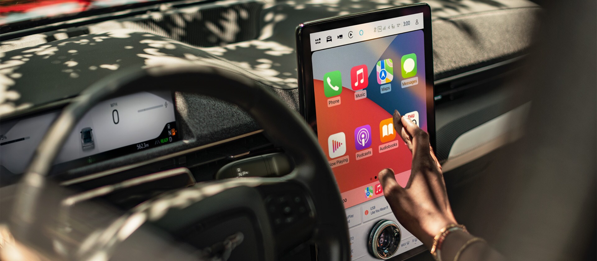 Een close-up van de bestuurder van een Ford Mustang Mach-E die het grote 15.5" SYNC 4-touchscreen met Apple CarPlay gebruikt. 