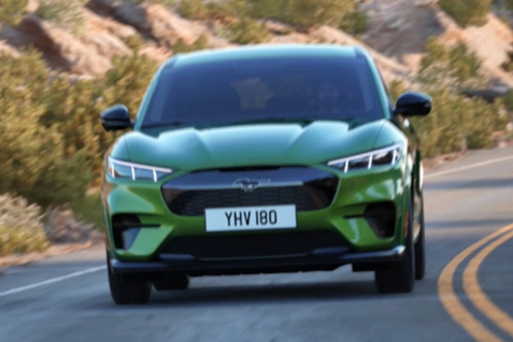 Vooraanzicht van groene Ford Mustang Mach-E rijdend op bergweg.