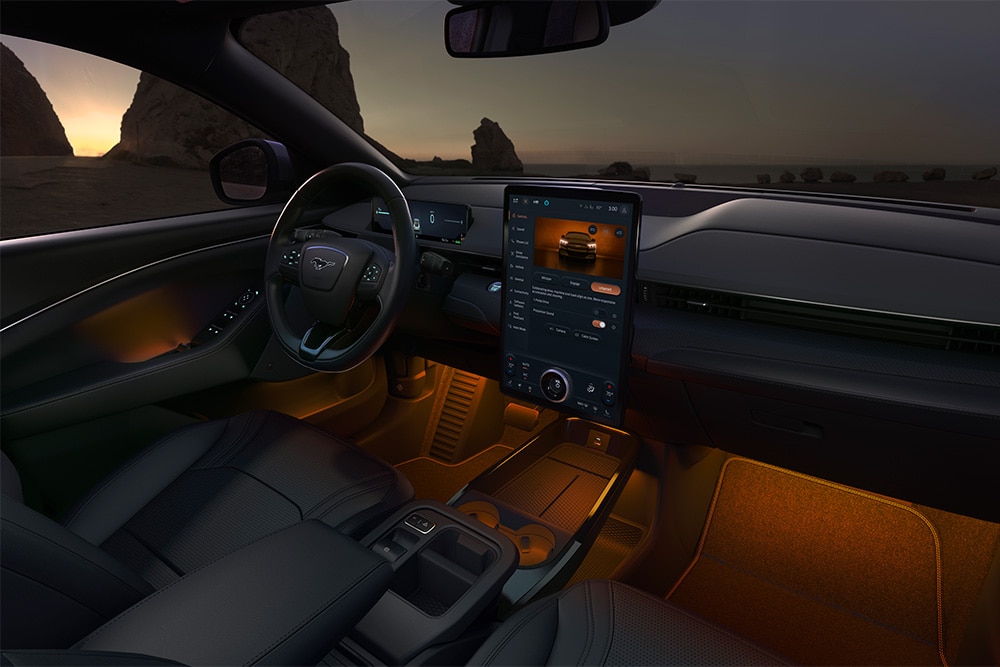 Het interieur van de Ford Mustang Mach-E in het donker, met het 15.5" SYNC 4-touchscreen en de omgevingsledverlichting ingesteld op oranje.