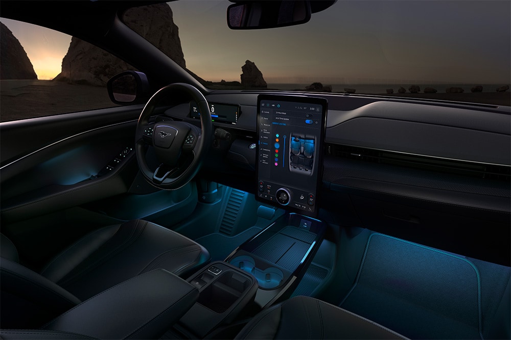Het interieur van de Ford Mustang Mach-E in het donker, met het 15.5" SYNC 4-touchscreen en de omgevingsledverlichting ingesteld op blauw.