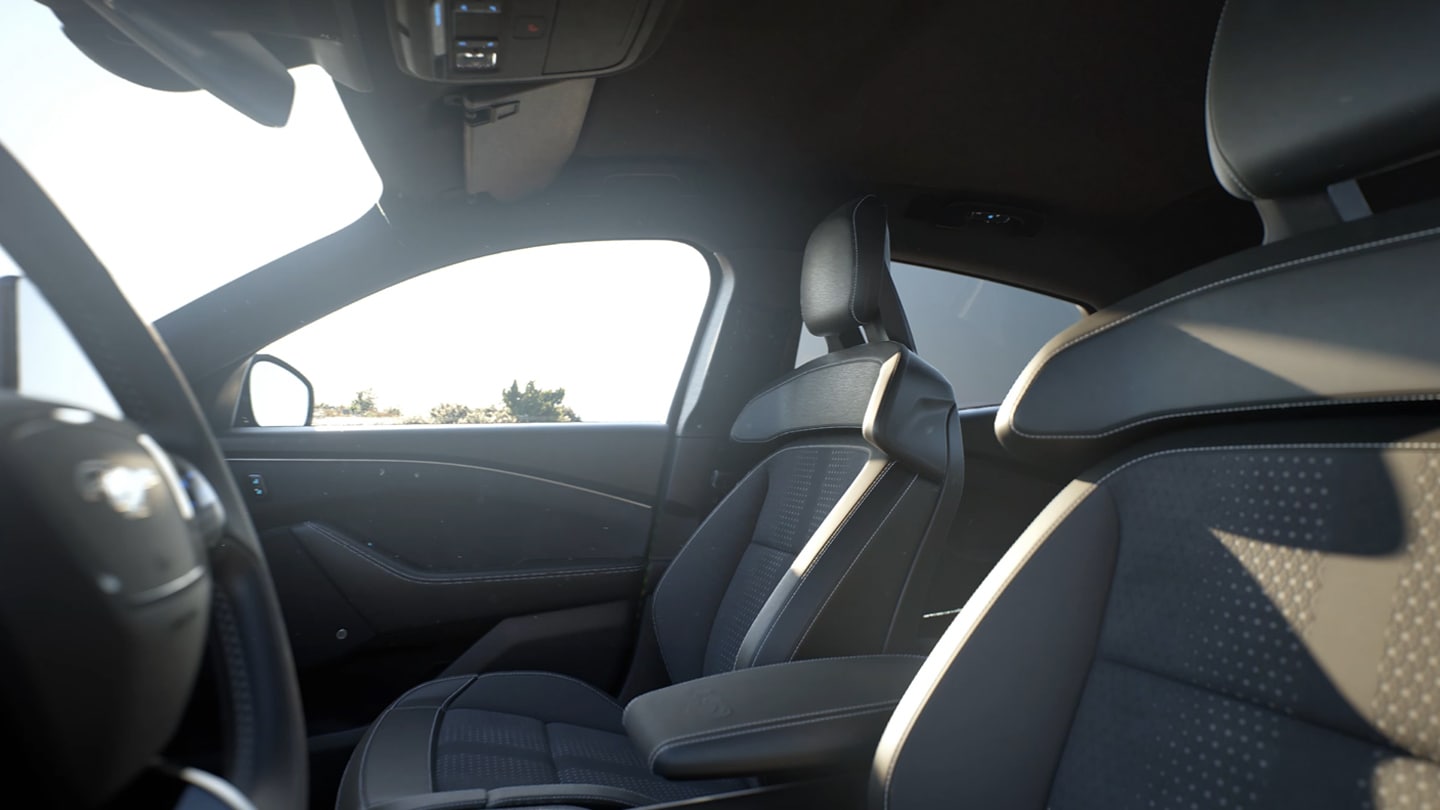 Het interieur van de Ford Mustang Mach-E, met de vijf comfortabele zitplaatsen afgewerkt in zwart materiaal met rode stiksels.