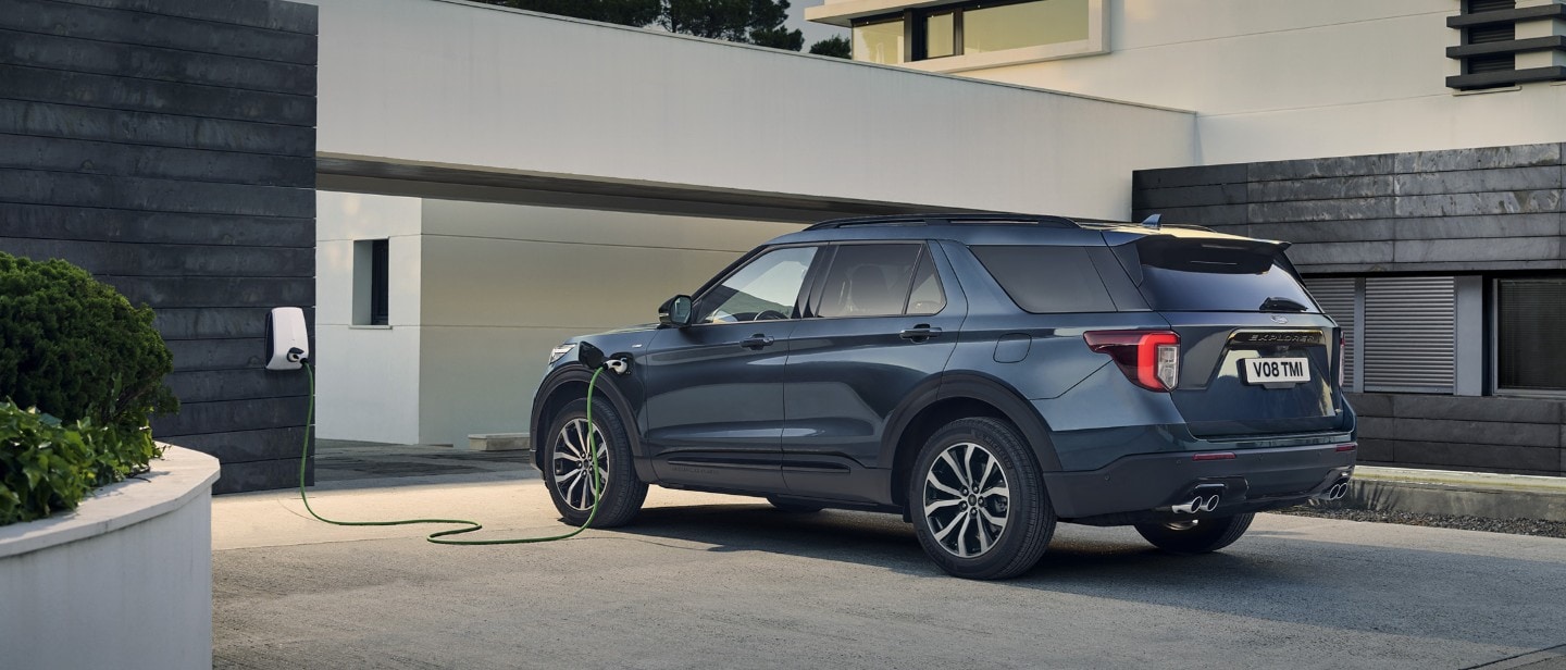 New metallic blue Ford Explorer PHEV parked and charged from the socket in the house