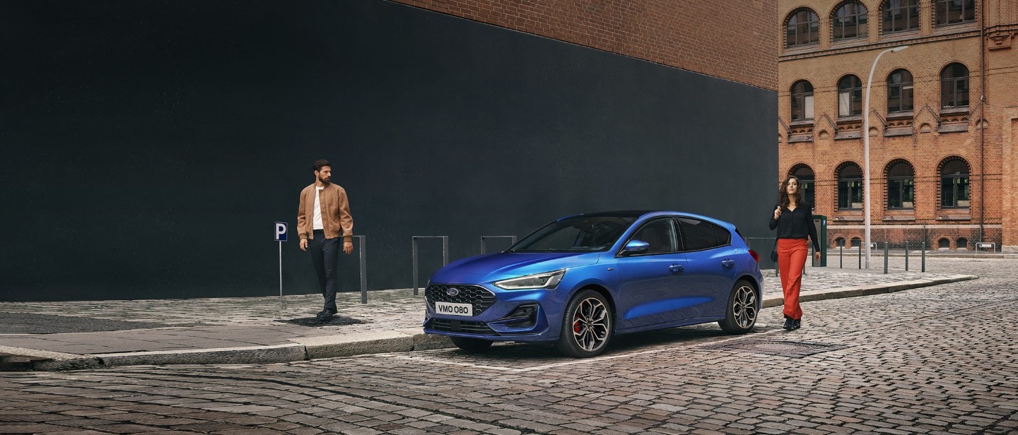 Blue Ford Focus parked next to a sidewalk