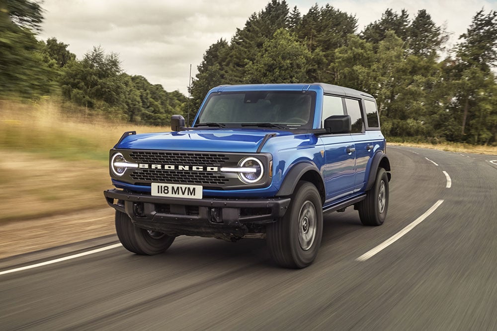 Vue de face du Ford Bronco bleu roulant sur une route de campagne.