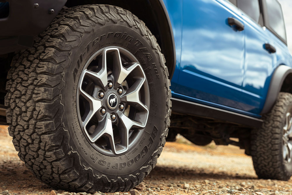 Gros plan sur les pneus tout-terrain d’un Ford Bronco bleu.