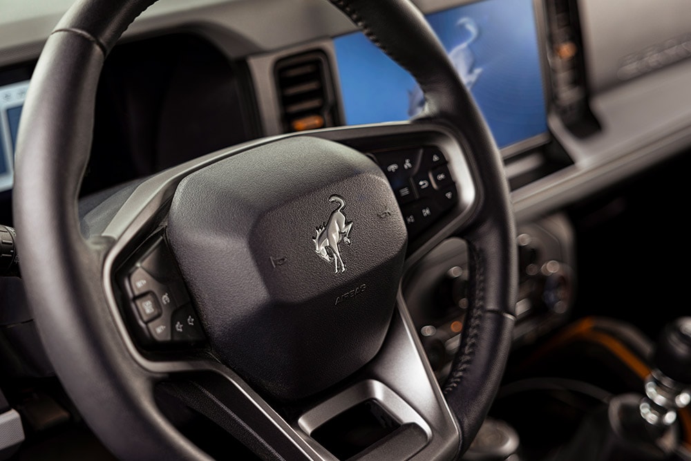 Gros plan sur le volant en cuir siglé du Ford Bronco.