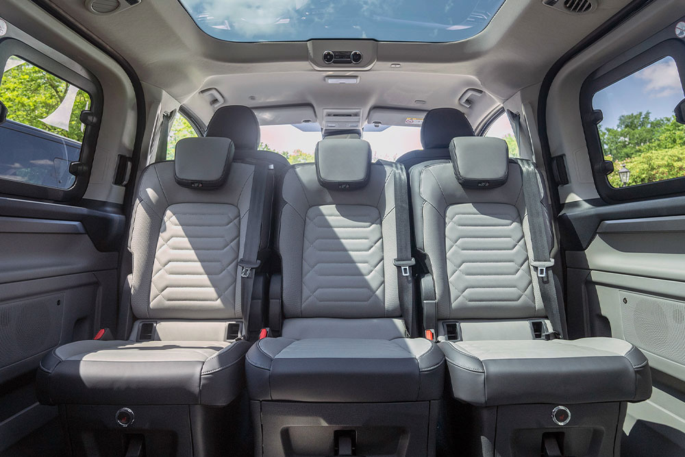 Vue intérieure d’un véhicule, montrant les sièges arrière gris et un toit ouvrant.