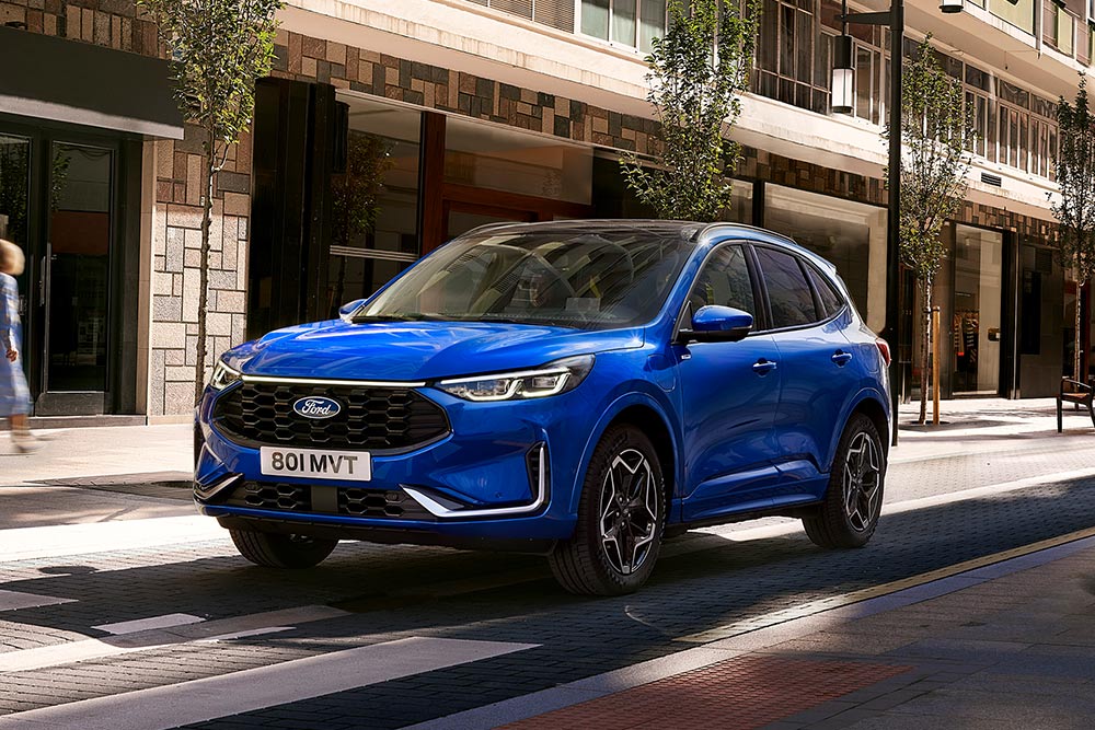 Ford Kuga bleu garé dans une rue de ville, vue de face 3/4.