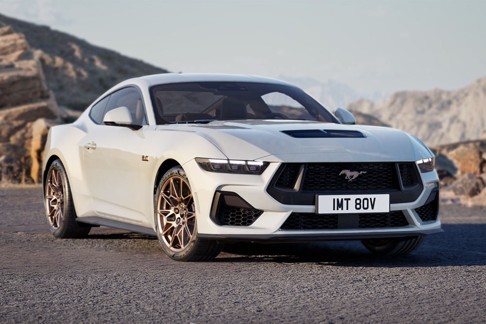Ford Mustang GT Fastback avec Bronze Pack en peinture Oxford White, garé sur une route de montagne