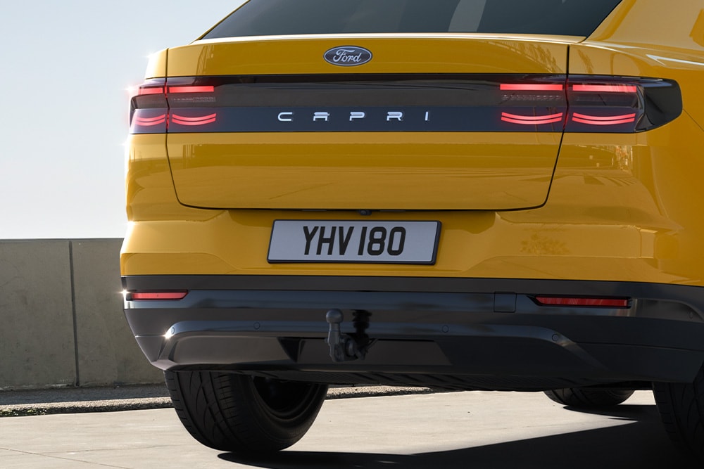 Vue arrière d’un Ford Capri® jaune circulant sur une route urbaine.