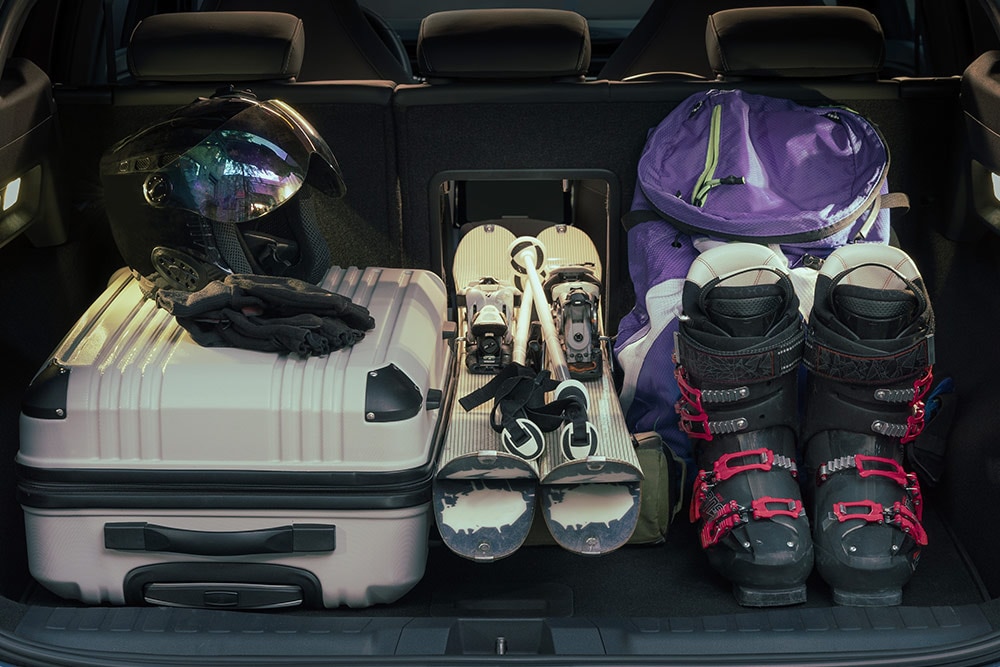 L'espace à bagages arrière du Ford Explorer, rempli d'une valise blanche et d'équipements de ski placés par la trappe à bagages.