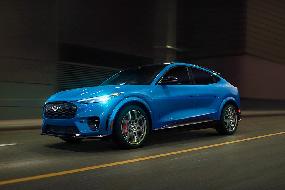 Une Ford Mustang Mach-E GT électrique bleue roulant sur une route dégagée.