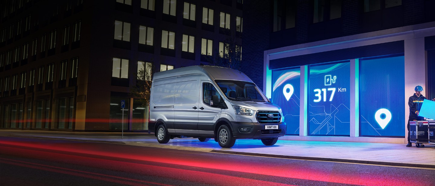 New Ford E-Transit in front of depot in city in night 3/4 front view