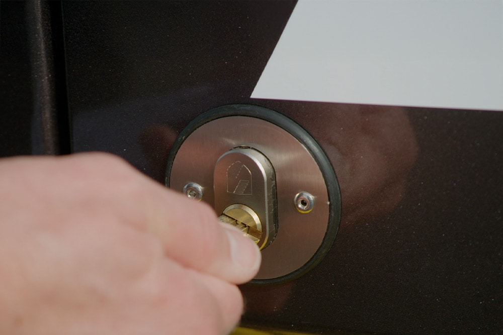 Une main verrouille la portière d'un fourgon avec une clé.