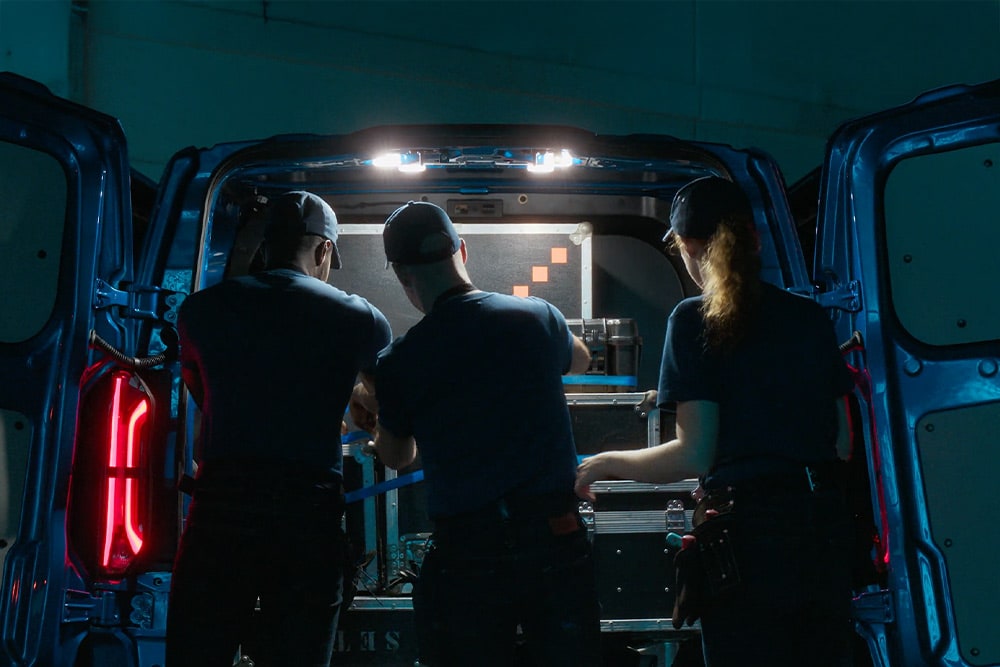 Trois personnes travaillent à l'arrière d'un fourgon Ford Transit Custom.