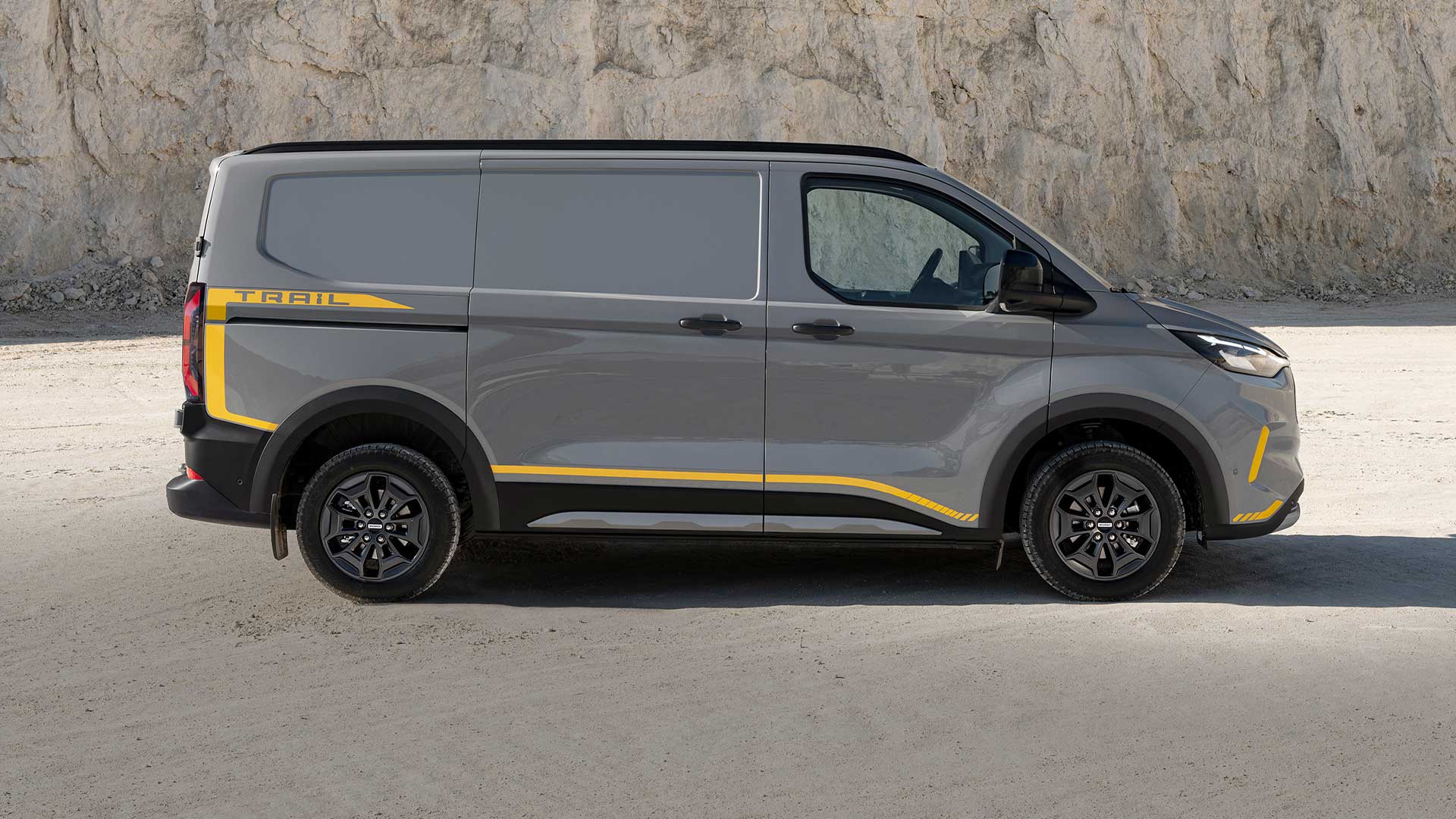 Fourgon Ford Transit Custom Trail gris avec des touches de jaune, vue latérale.