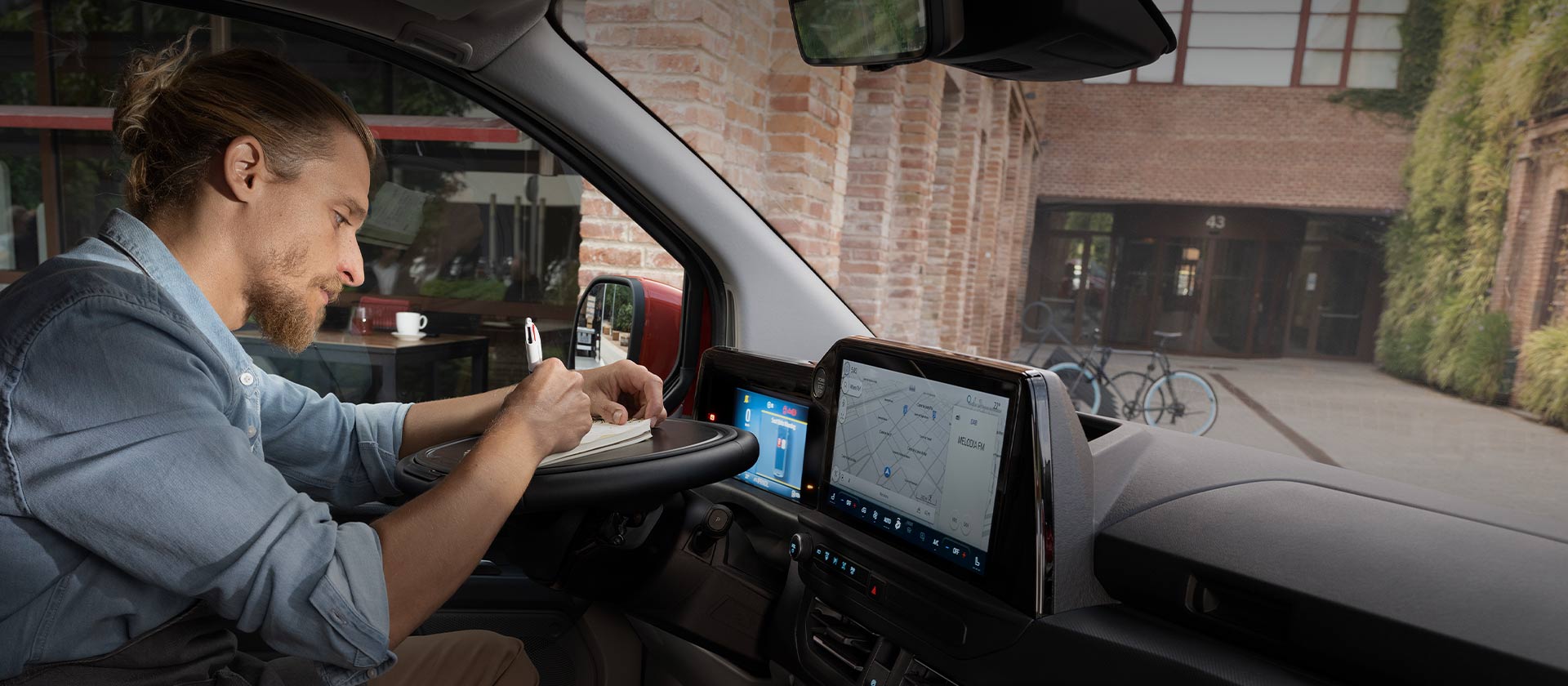 Une personne écrit dans un carnet à l'intérieur d'un Ford Transit Custom.