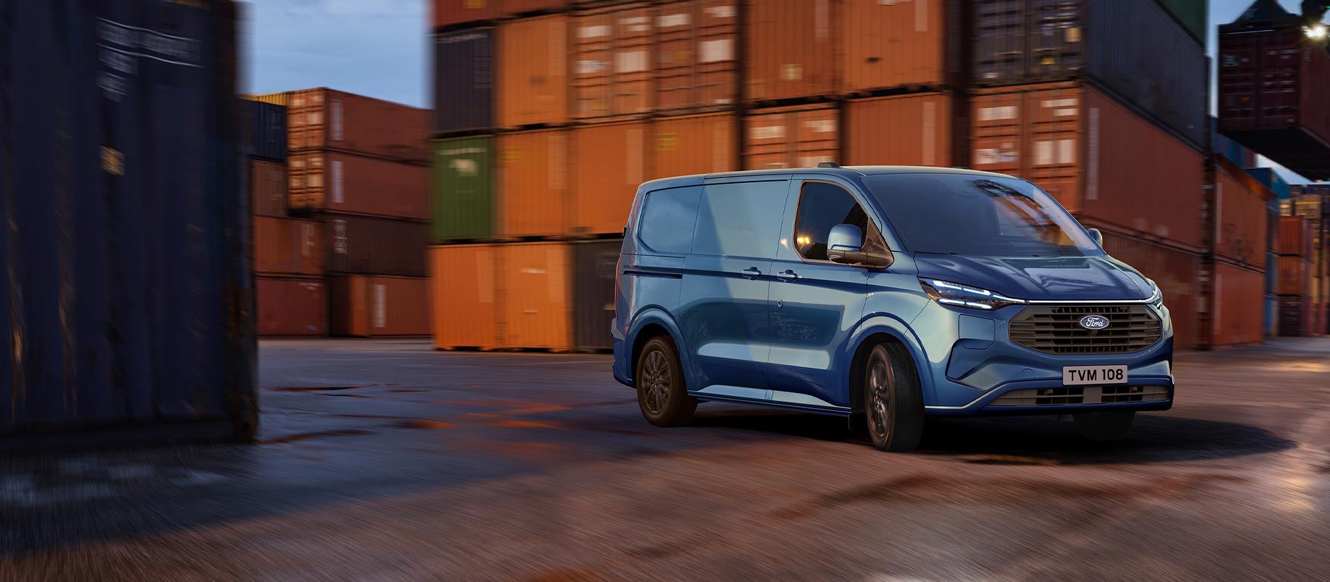 Un fourgon Ford Transit Custom Plug-in Hybrid bleu roule sur les quais d'un port.