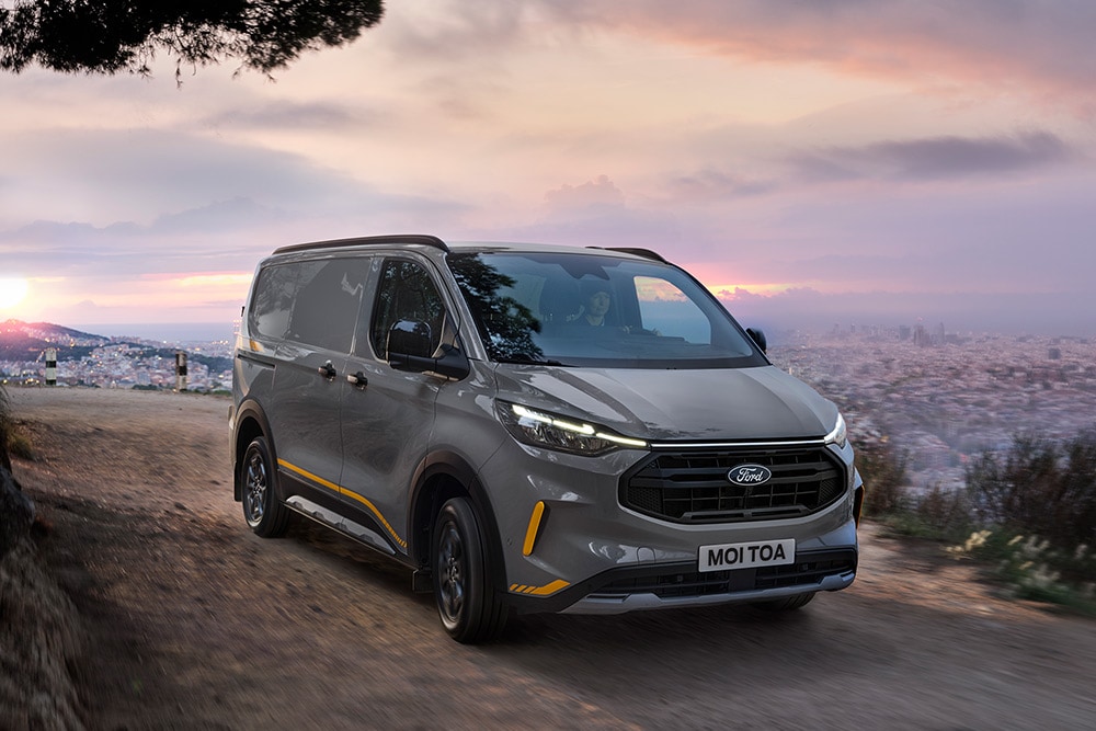 Fourgon Ford Transit Custom Trail gris avec des touches de jaune.