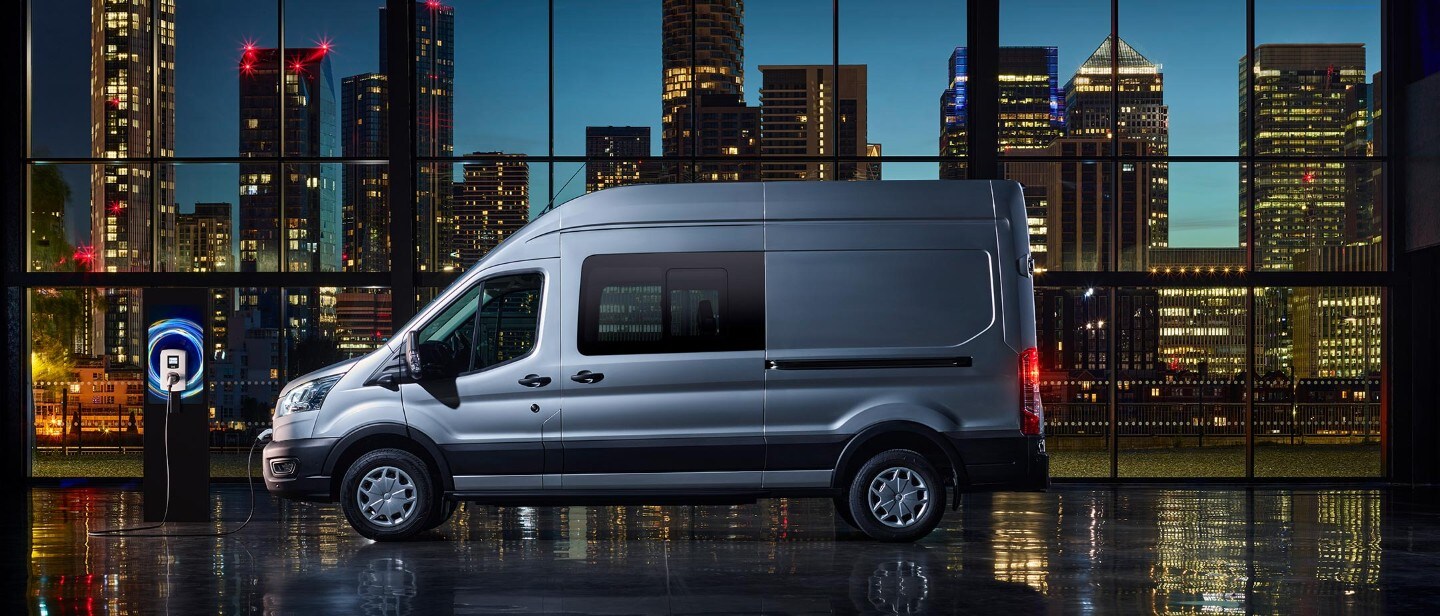 New E-Transit side view with the backdrop of city in night with blue electric lights