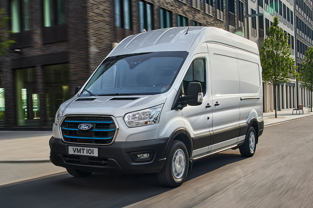 Fourgon Ford E‑Transit argenté circulant en ville.