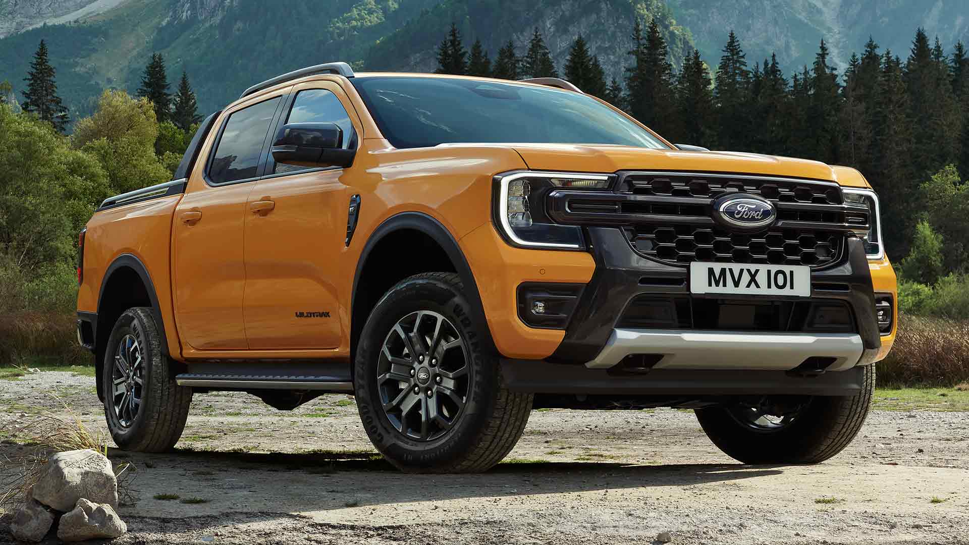 Ford Ranger Wildtrak Double Cabine jaune dans une forêt pittoresque et un arrière-plan montagneux.