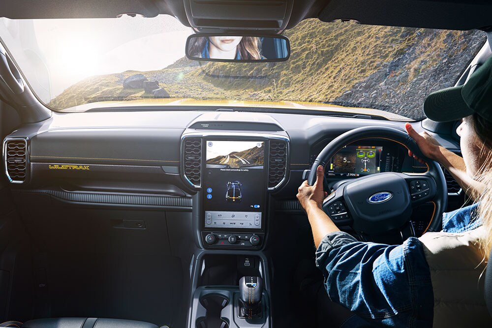Conducteur tenant le volant du Ford Ranger tout en roulant sur une piste de montagne sinueuse.