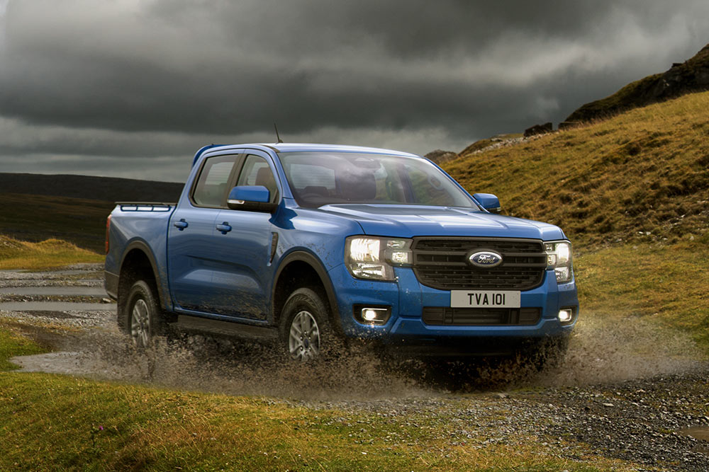 Un Ford Ranger bleu patauge dans un paysage accidenté.