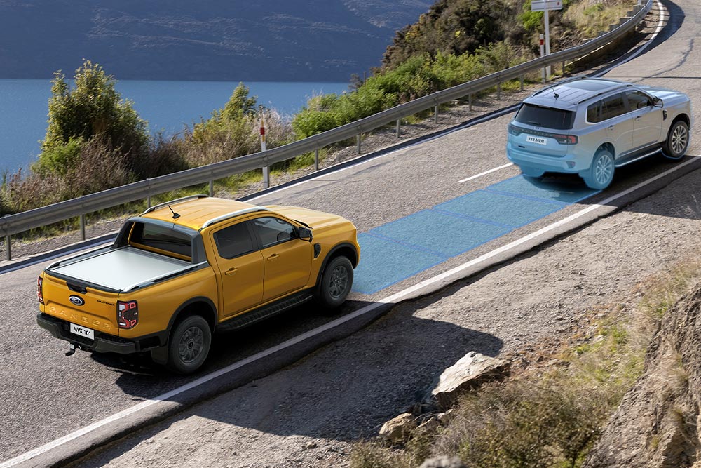  Un Ford Ranger jaune utilise son système avancé d'aide à la conduite le long d'une autoroute côtière. 