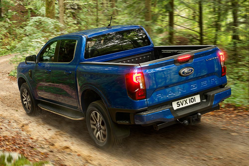 Feu arrière et hayon d'un pick-up Ford Ranger bleu roulant sur un chemin de terre.