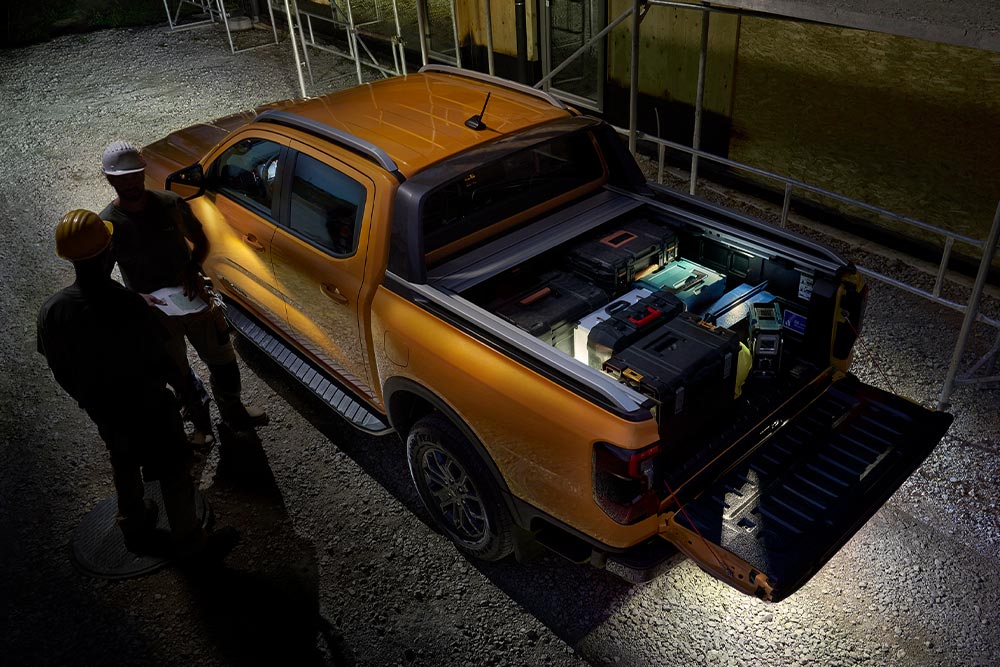 Vue aérienne nocturne du Ford Ranger Wildtrak jaune avec éclairage de zone extérieur.