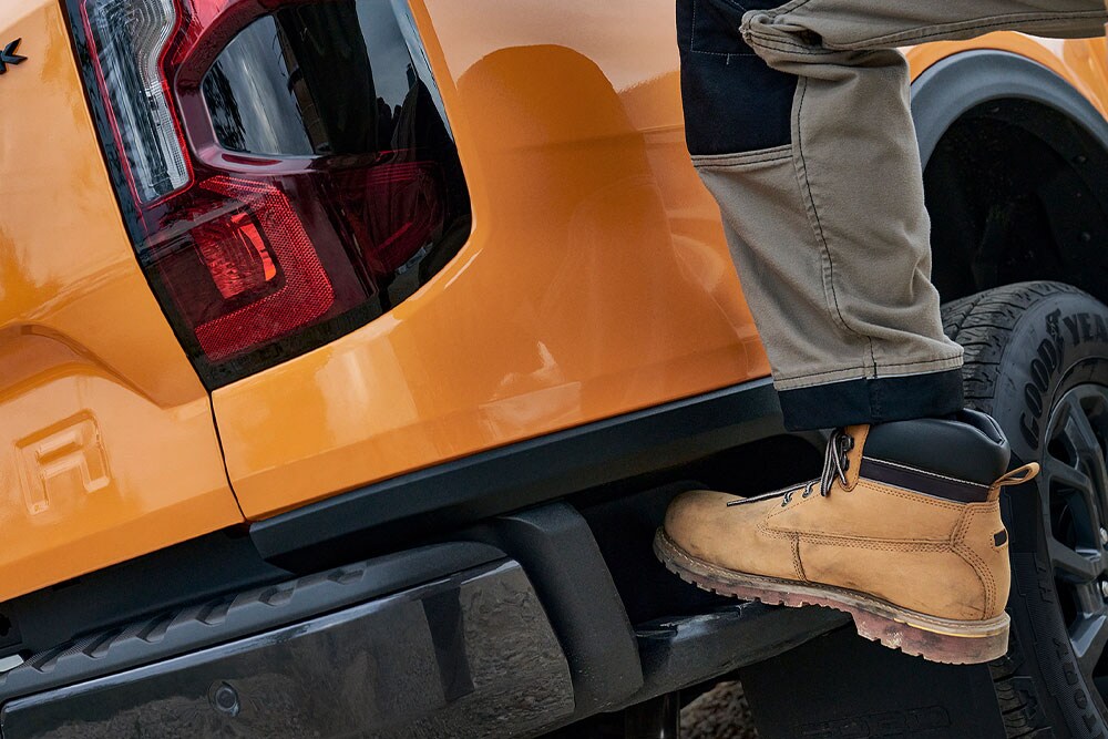 Travailleur qui monte sur le marchepied arrière intégré du Ford Ranger Wildtrak.