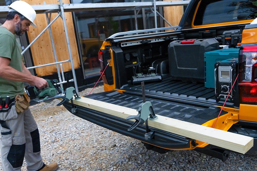 Une personne travaillant au hayon ouvert d'une Ford Ranger Double Cabine jaune.