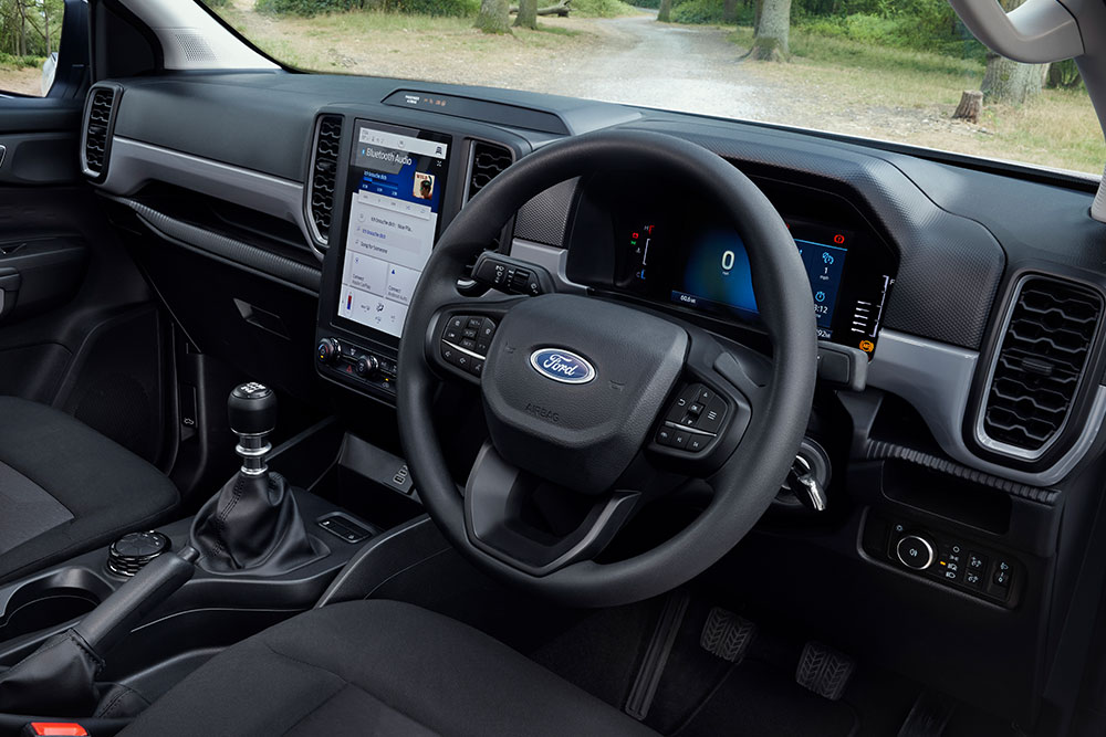 Vue intérieure de la cabine du Ford Ranger, mettant en avant le volant et le levier de vitesse manuel.