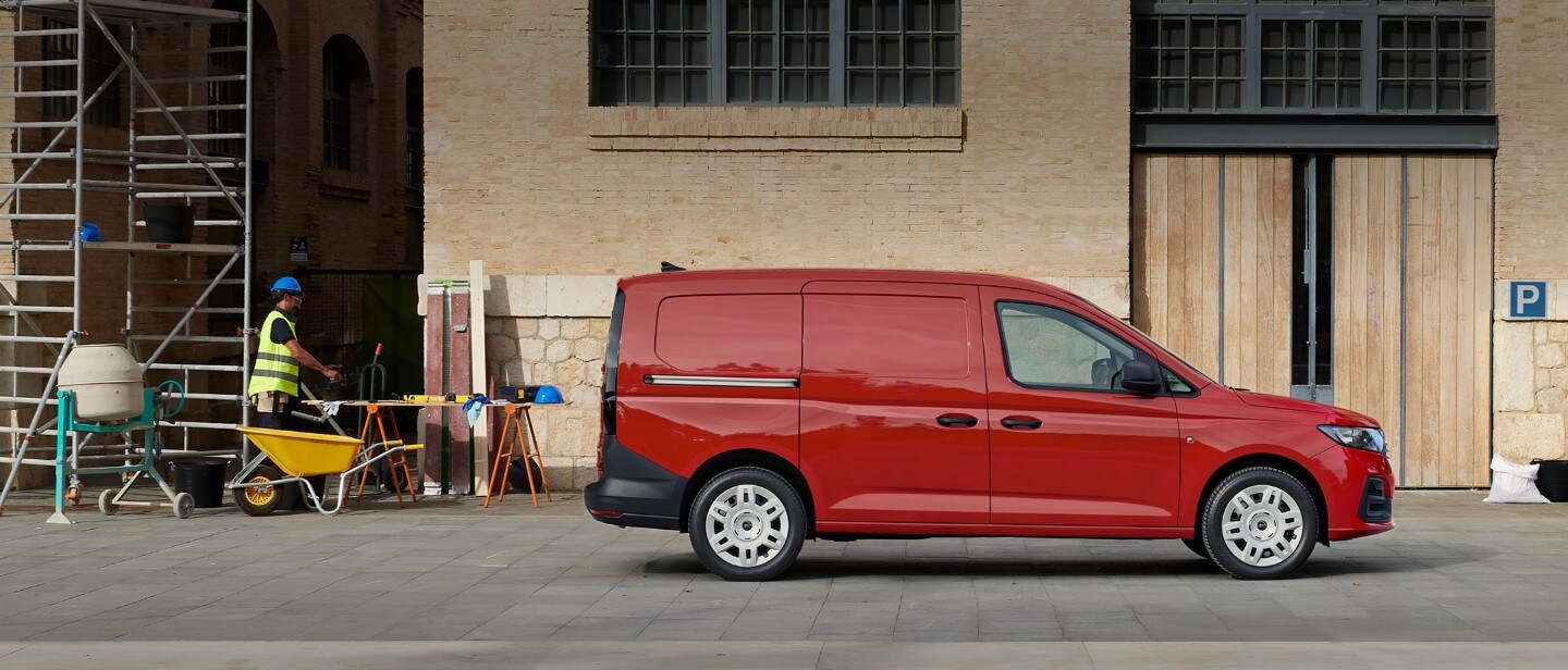 Le nouveau Ford Transit Connect en Maple Red est garé au milieu d'un chantier de construction affichant une porte de chargement latérale.
