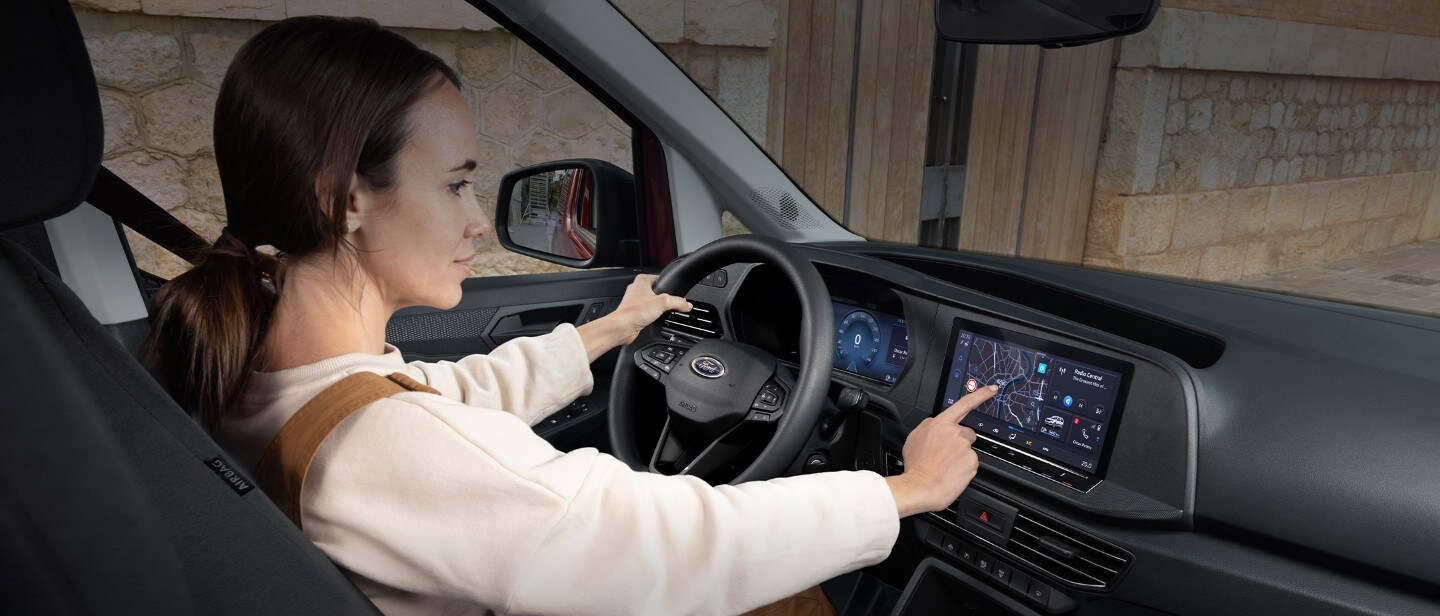 Une femme touche l'écran tactile de 10 pouces alors qu'elle est assise dans le siège conducteur du nouveau Ford Transit Connect.