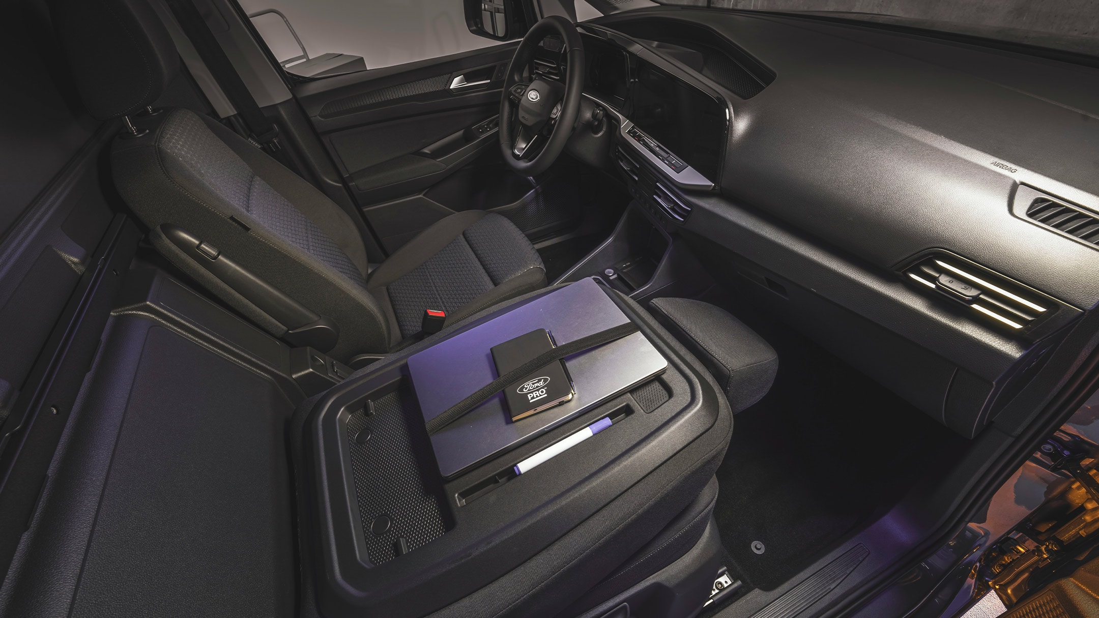 Un ordinateur portable et un notebook Ford Pro reposent sur la table de travail du nouveau Ford Transit Connect.