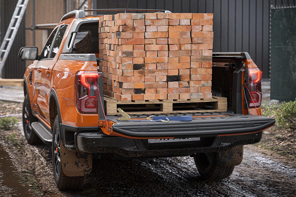 Vue arrière d’un Ford Ranger orange avec un tas de briques chargé sur la plateforme.