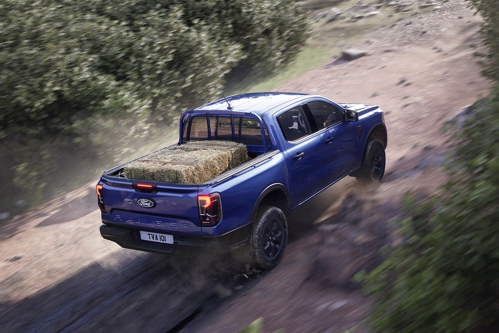 Vue de dessus arrière d’un Ford Ranger bleu roulant sur un chemin de terre.