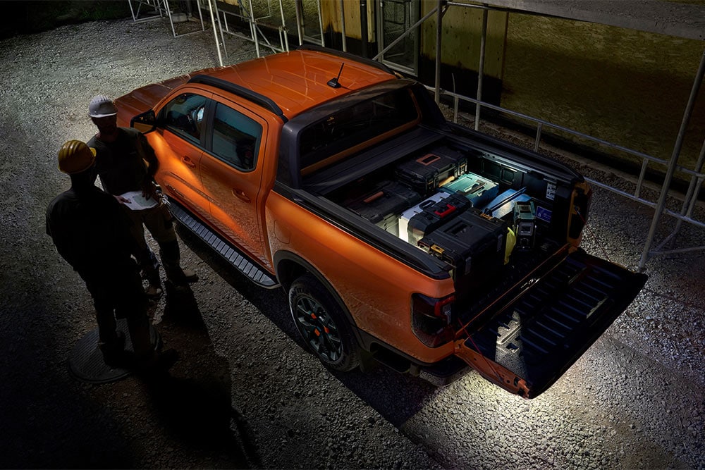 Vue de dessus d’un Ford Ranger Wildtrak orange de nuit avec éclairage de zone extérieur.