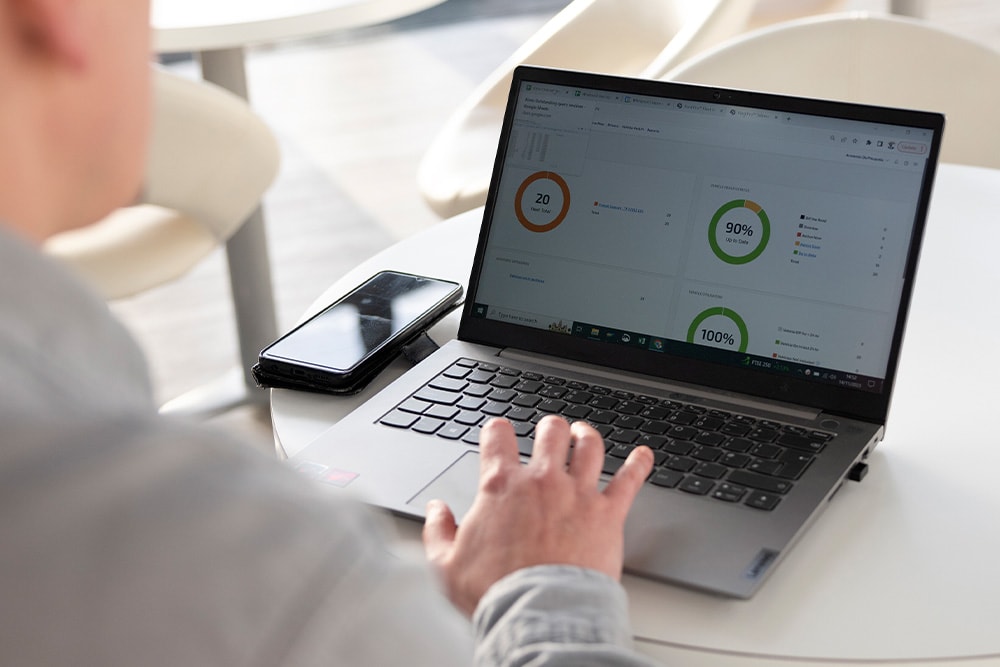Une personne sur un ordinateur portable passant en revue le tableau de bord de Ford Pro Telematics, avec différentes mesures de performance de la flotte.