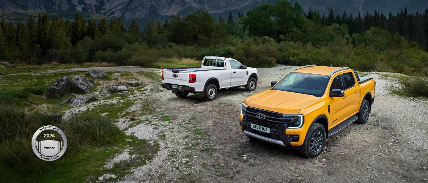 Orange Ford Ranger 3/4 front view on gravel in front of White Ford Ranger 3/4 rear view